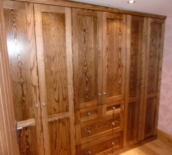Ash bespoke fitted wardrobes with drawers, half hanging in the centre with double hanging space at each end.