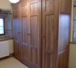 Solid Oak Semi Fitted Wardrobes feature panelling to match a four poster bed.  Built in a traditional style for a 17th century period property.