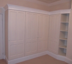 Bespoke fitted wardrobes built with panelled doors & an open shelving unit.  