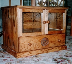 A glass fronted display cabinet built in Ash to house video/DVD. The unit incorporates a drawer to the bottom with carved detail. Built for client in Wrose, Shipley