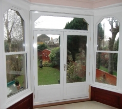 Hardwood  Double French Doors built with toughened sealed double glazed units & panels to the bottom. Shaped glazed unit above the doors is built to match the windows on either side.