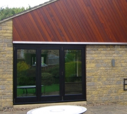 Hardwood folding doors built using the P C Henderson sliding door system. The doors are 60mm thick Iroko hardwood. When opened the doors give full access to the outside patio area.