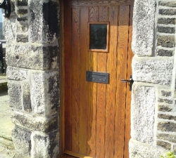 A solid Ash, panelled external cottage door with a small viewing window.