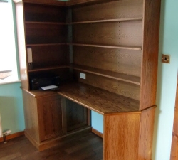 An Oak corner desk unit incorporating shelving and a lockable base unit. Built as a set of three together with an Oak bookcase and display unit.