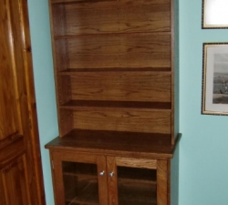 A free standing Medium Oak bookcase with glass fronted storage to the base. Built as a set of three together with a desk unit and display unit.