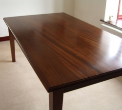 A Sapelle, hardwood dining table with tapered legs. Stained to match the existing furniture in the home and completed with a lacquered finish.
