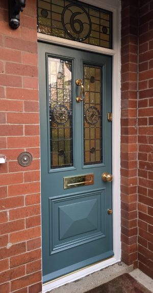 Blue-grey bespoke Accoya front door with handcrafted stained glass panels, brass ironmongery and stained glass house number, installed at a period property in Harrogate.